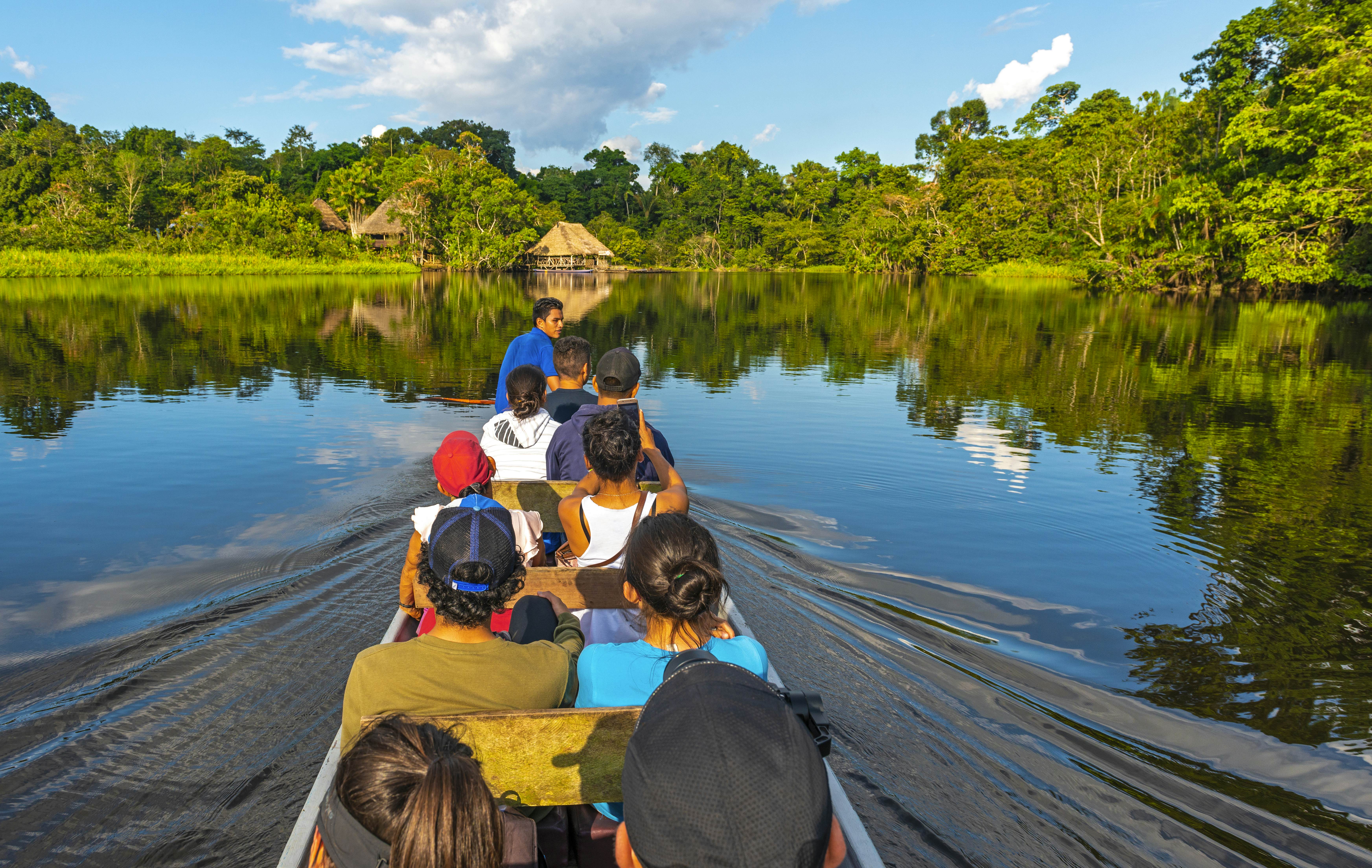 Transport in canoe along the rivers of the Amazon River Basin inside the Yasuni National Park with a view of a lodge in traditional style, Ecuador.